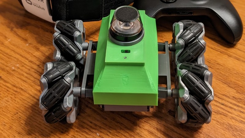 Showing the end result car, with mechanum wheels and a green chassis with what seems to be a camera window on top